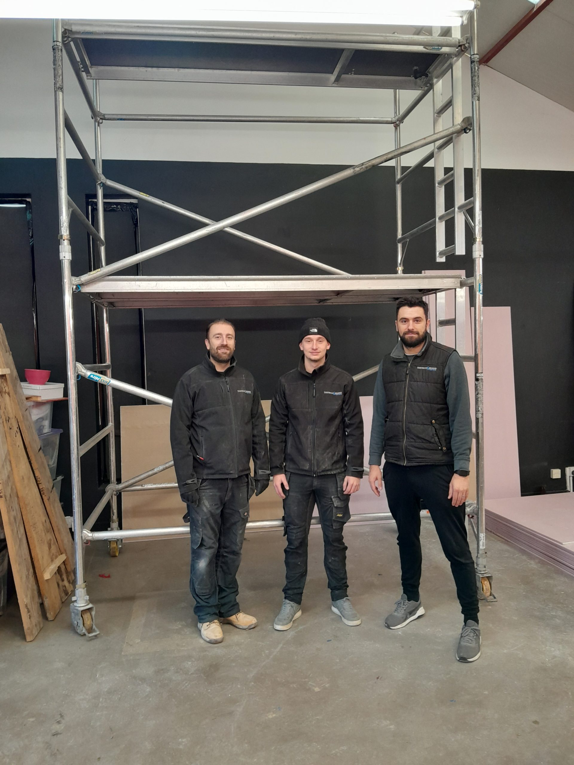 Three young men standing under scaffolding